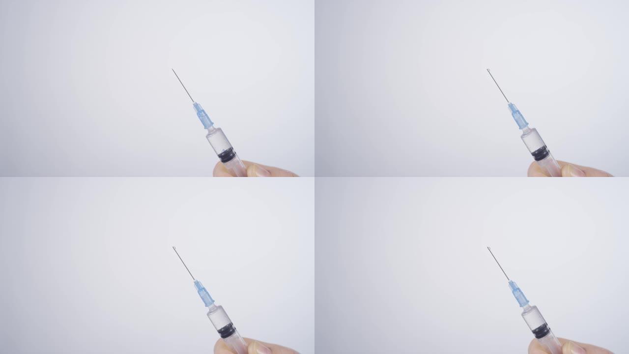 特写: 从注射器中喷出的透明疫苗的详细镜头。