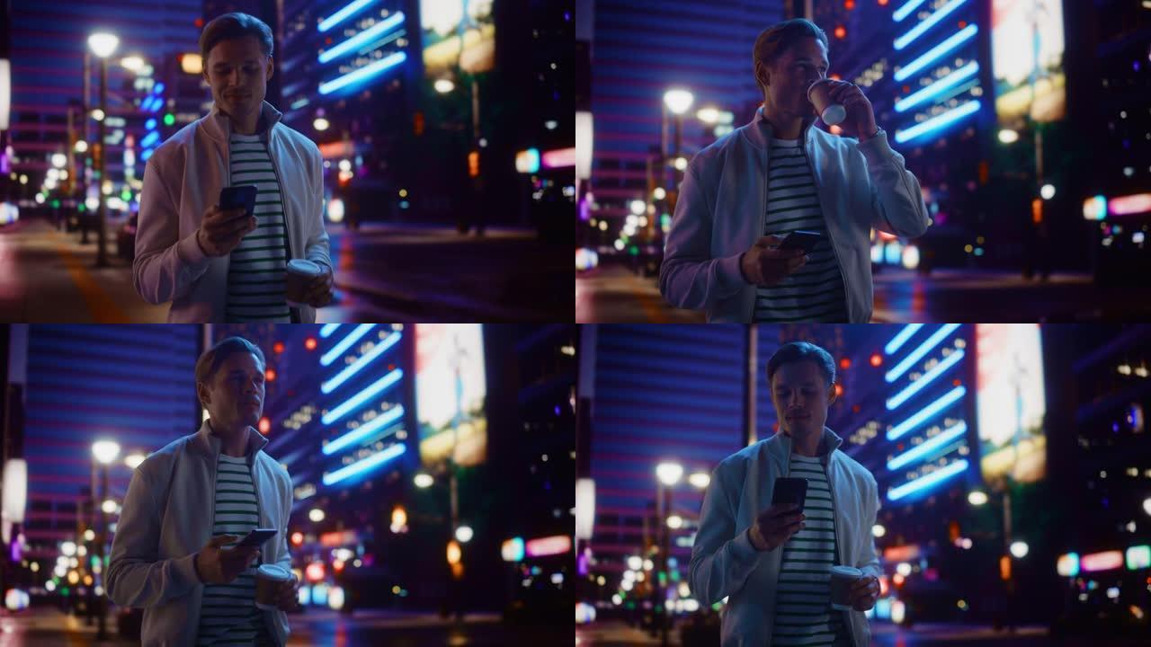 男人使用智能手机，喝饮料，穿过充满霓虹灯的夜晚城市街道。微笑的时尚男人使用手机，社交媒体，在线购物，