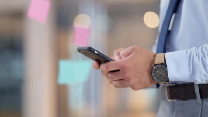 Businessman texting an email on his phone in a mod