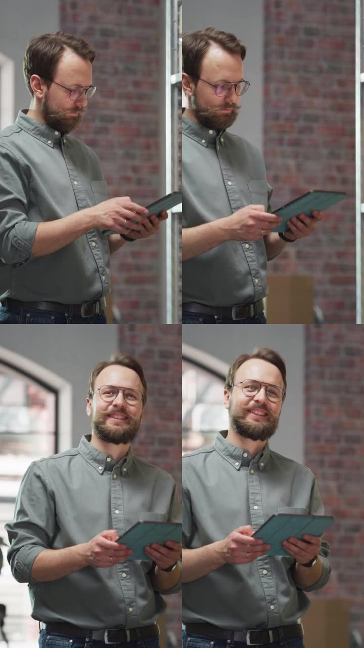 成功的小企业主使用平板电脑检查库存的垂直肖像。留着小胡子的英俊男人摆姿势拍照，在仓库储藏室里微笑着，