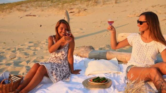 WS两名年轻妇女在沙滩上举杯酒
