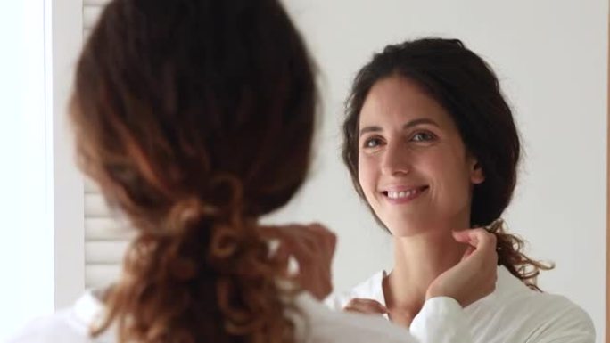 35岁的女人照镜子欣赏健康完美无瑕的面部皮肤