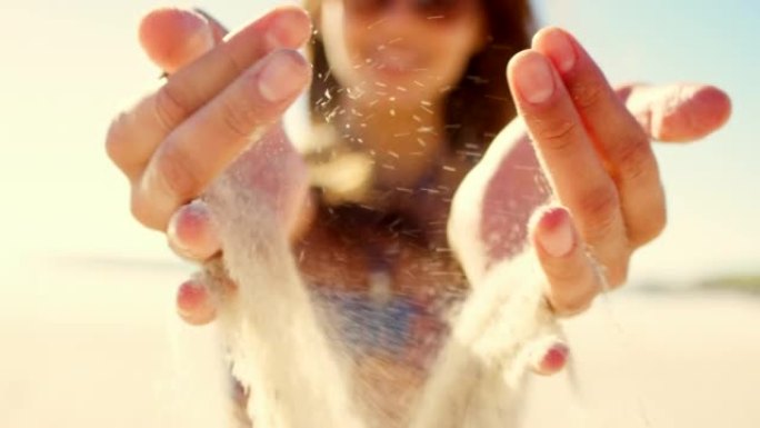 4k视频片段，一名妇女在沙滩上用手倒沙子