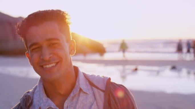 一个英俊的年轻人在日落时独自站在海滩上的4k视频片段
