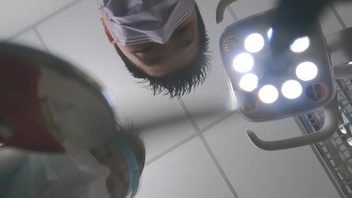 亚洲中国男性牙医牙髓病专家，戴着放大镜，从上方看光线