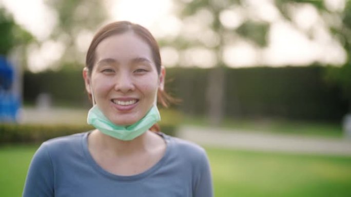 年轻的亚洲妇女脱下她的防护面罩，微笑着
