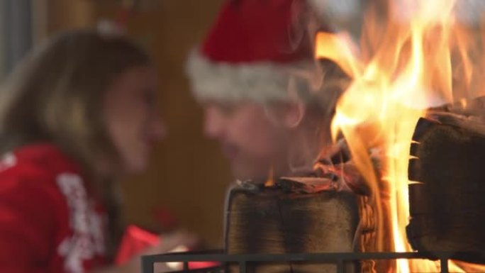 特写: 点燃的壁炉和男人在背景中给女人圣诞礼物