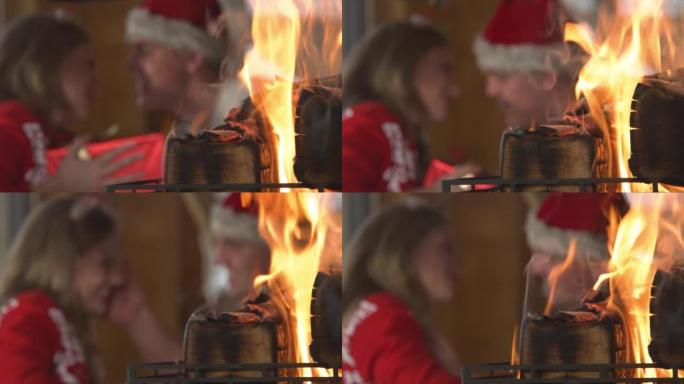 特写: 点燃的壁炉和男人在背景中给女人圣诞礼物