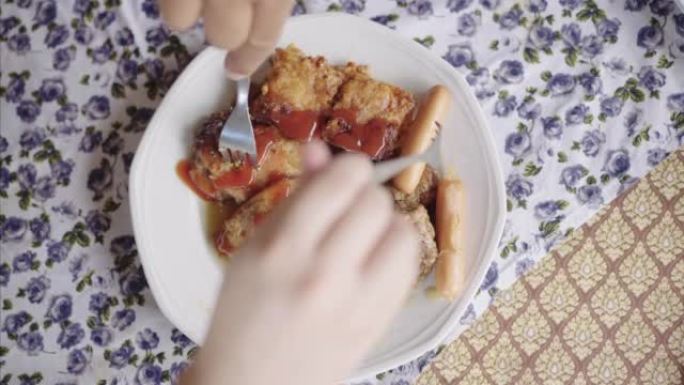 SLO MO: 人类双手在餐桌上分叉食物的俯视图，包括烤猪肉，肉丸和炸薯条。