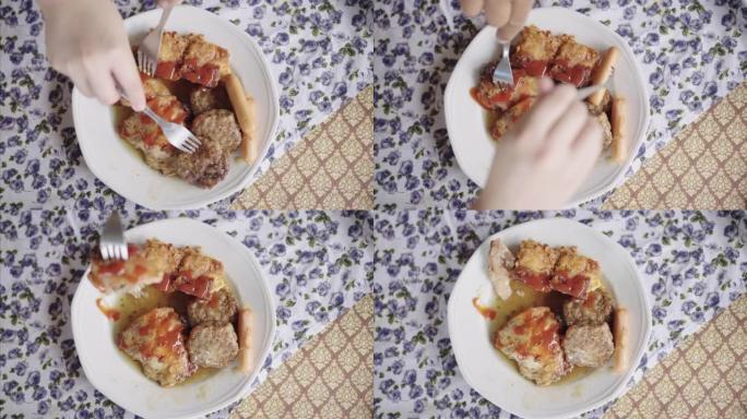 SLO MO: 人类双手在餐桌上分叉食物的俯视图，包括烤猪肉，肉丸和炸薯条。