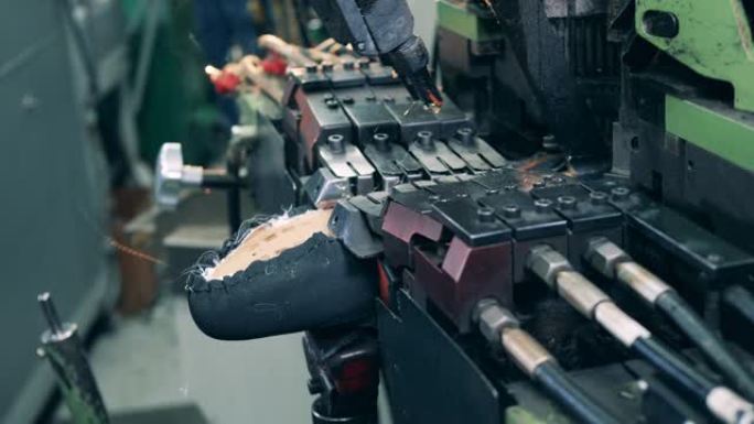 工厂机器正在将胶水涂在鞋底上。鞋类生产设施。