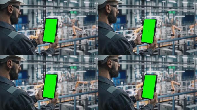 汽车工厂工程师在工作制服中使用带有绿屏模型显示的平板电脑。汽车工业制造工厂的增强现实软件致力于车辆生