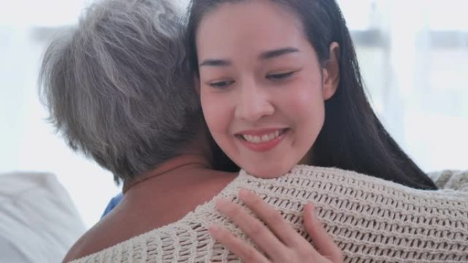 亚洲老年妇女在家里听亚洲年轻女护士医生咨询并拥抱她的老年女病人。在家护理人员