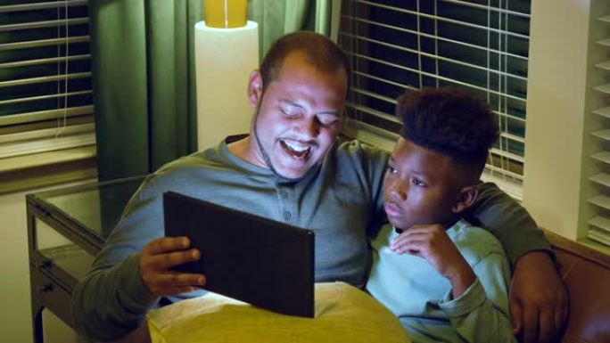 多种族的父亲和继子看着数字平板电脑