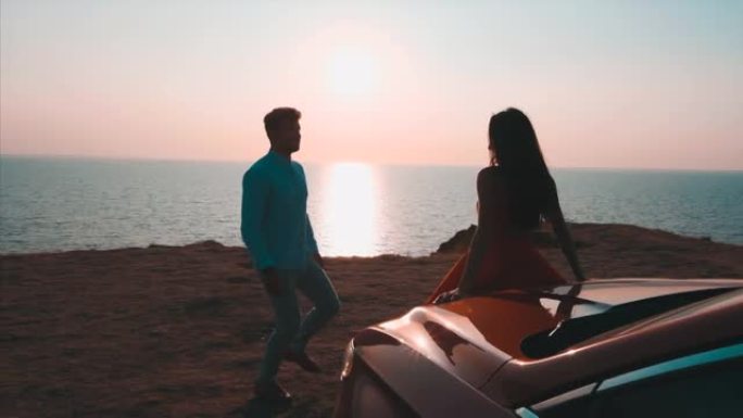 浪漫的夫妇站在海景背景上的汽车附近。慢动作