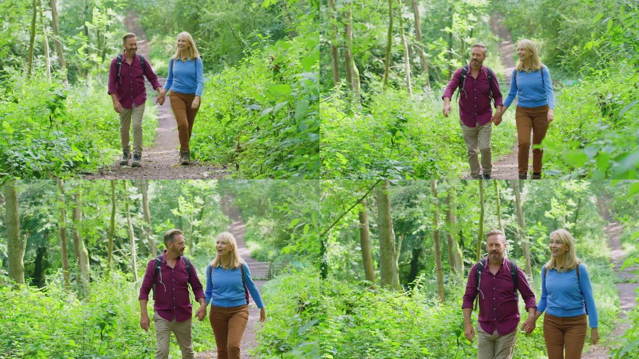 乡间相爱的成熟夫妇手牵着手在森林里徒步旅行