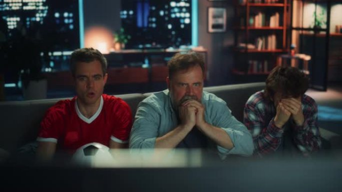 晚上在家: 三个快乐的足球迷坐在电视上的沙发上观看比赛，当运动队赢得冠军时，他们担心并庆祝胜利。一群