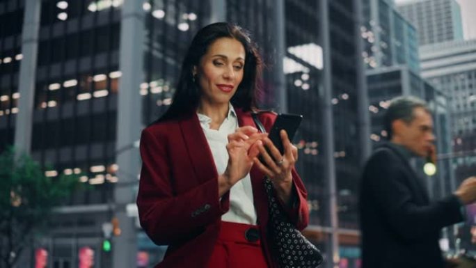 一个美丽的成年女商人在大城市的街道上使用智能手机的肖像。自信的经理在去办公室的路上与网上的人联系，发