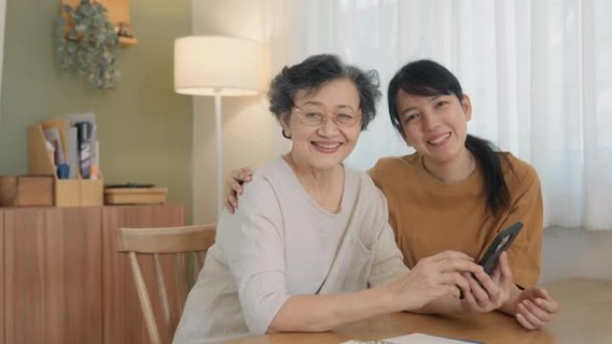 亚洲孙女的肖像教学母亲80年代祖母使用智能手机