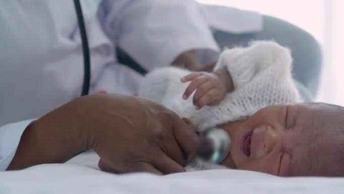 女医生的非洲民族儿科医生使用听诊器听心脏到新生儿年龄1个月在医院哭泣，儿童保健医生和病人的咨询理念。
