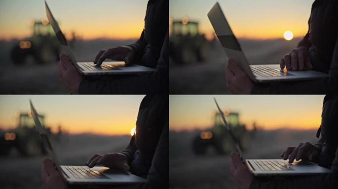 太阳升起时，在农田里使用笔记本电脑的男性农民特写