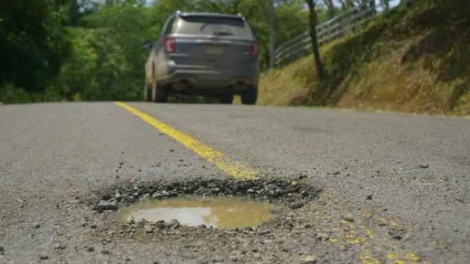 特写，dop: 4x4车辆在探索巴拿马时躲开了道路上的一个大洞。