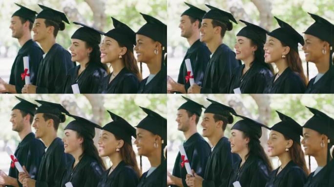 一群穿着砂浆板和长袍的大学或大学毕业生在外面的毕业典礼上排队。获得教育成功后持有学位或文凭的骄傲学生