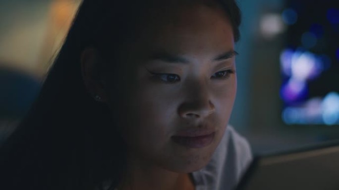 亚洲女性在晚上使用平板电脑