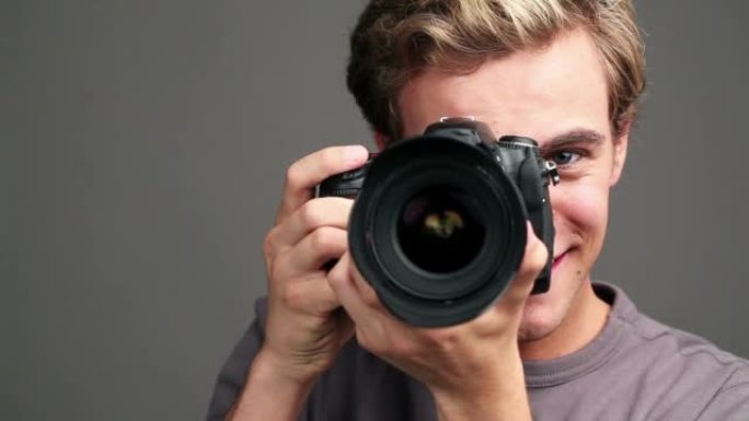 一名年轻男性摄影师在工作室背景下拍摄视频的4k视频片段