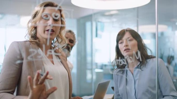 使用便签的商务人士集思广益团队领导女性与同事一起在玻璃白板上写作，在办公室会议上展示解决问题的策略