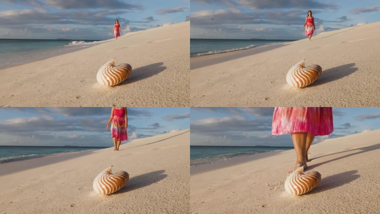女人走在海滩上，前景是美丽的鹦鹉螺贝壳