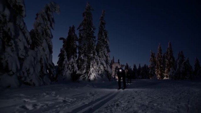 SLO MO越野滑雪者在晚上用大灯滑雪