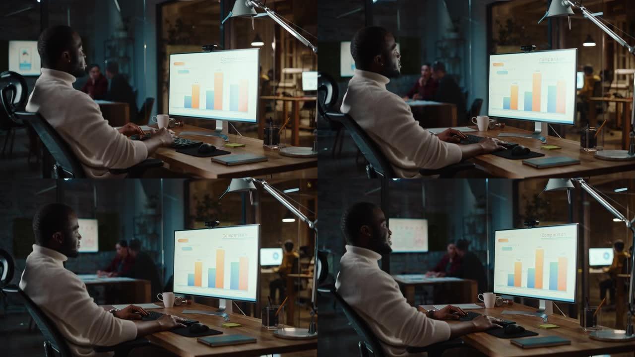 英俊的黑人非洲裔美国项目经理正在繁忙的创意办公室里的台式电脑上进行视频通话。首席策略师在镜头前交谈时