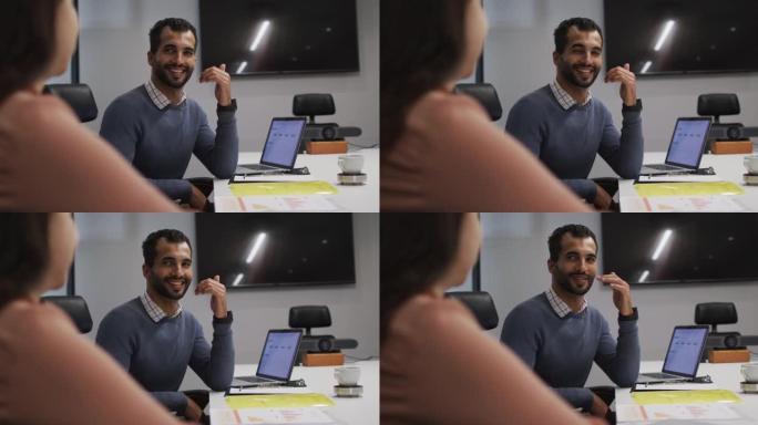 中东男子在办公室会议室看着他的女同事时微笑着