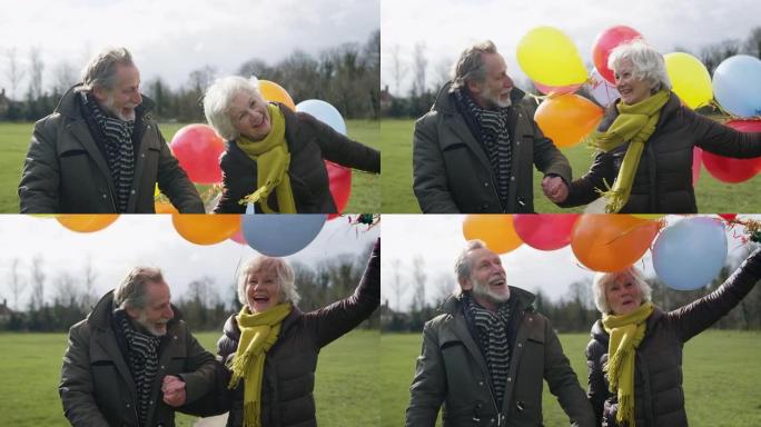 充满爱心的老年夫妇拿着气球享受秋天或冬天一起穿过公园