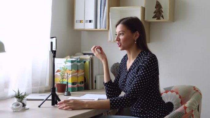 女性视频记录器坐在办公桌前记录新的视频日志使用智能手机