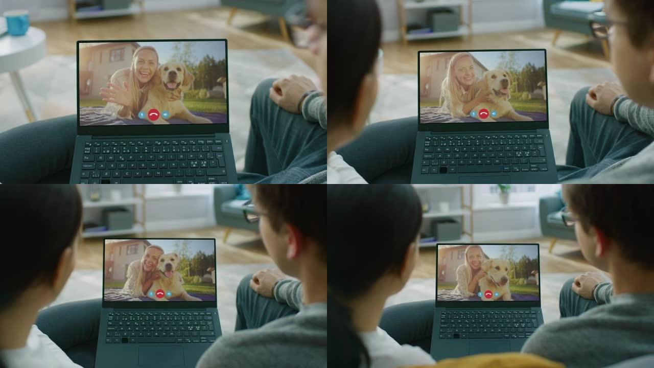 肩膀上的夫妇坐在笔记本电脑的沙发上，使用视频聊天与快乐的年轻女性朋友或与有趣的金毛寻回犬一起玩的家庭
