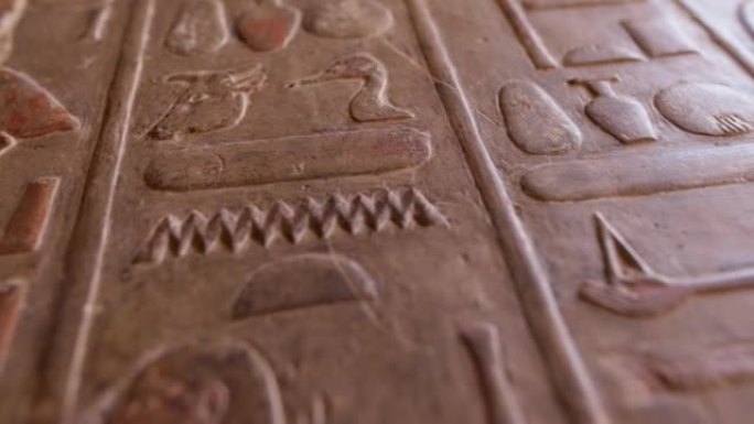 古埃及象形文字雕刻的仿古石墙。哈特谢普苏特神庙墙上的埃及象形文字的近景。浅景深，万向节射击