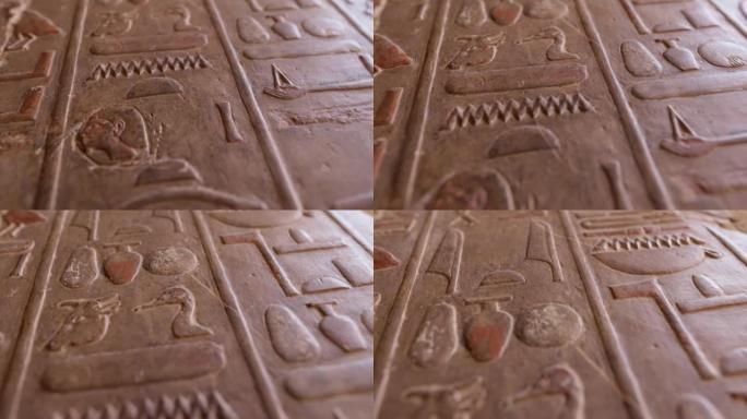 古埃及象形文字雕刻的仿古石墙。哈特谢普苏特神庙墙上的埃及象形文字的近景。浅景深，万向节射击