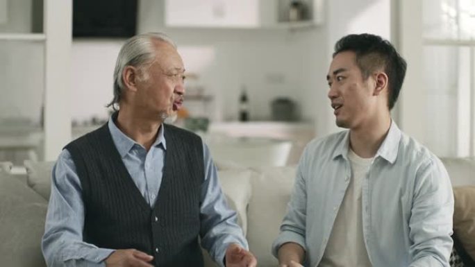 资深亚裔父亲和成年儿子在家聊天