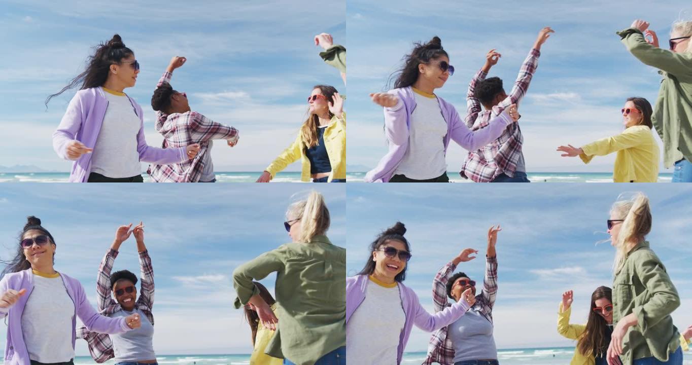 快乐的一群不同的女性朋友在海滩上玩得开心，跳舞和微笑