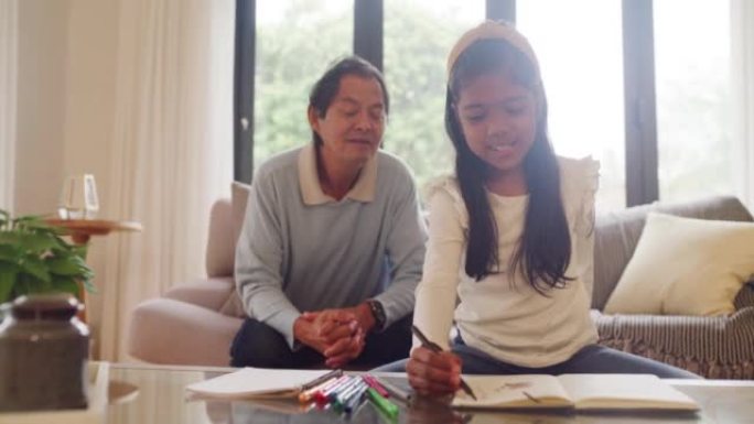 祖父与他的孙女在图画书中画画时建立了联系。快乐的女孩在拜访期间做作业并与爷爷建立联系。帮助孩子学习的