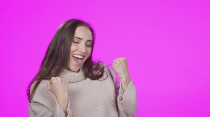 4k视频片段，一位迷人的年轻女子在粉红色的工作室背景下庆祝