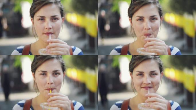 4k视频片段，一名年轻女子在城市外出时享受橙汁