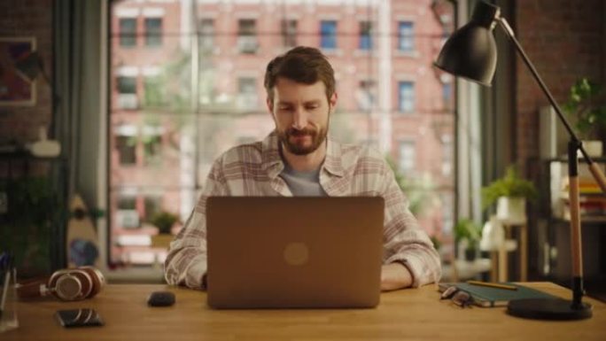 一个英俊的男人坐在时尚舒适的阁楼客厅时在笔记本电脑上工作的肖像。自由职业者在家从事商业项目，企业身份
