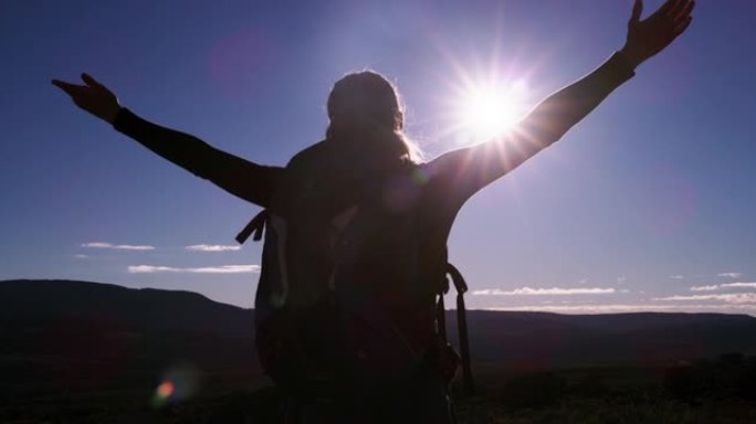 4k视频片段，一名年轻女子举起手臂，看着山上的风景