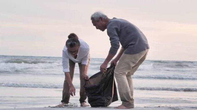 亚洲老年夫妇的志愿者在海滩上清理垃圾袋。当地清理概念。