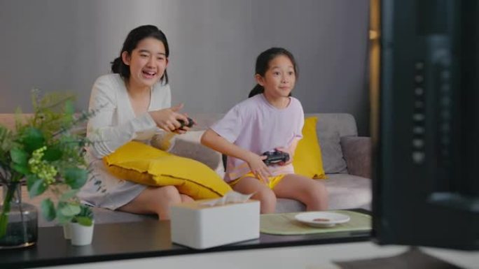 两个亚洲兄弟姐妹少年女孩在与兄弟在家里玩游戏机时击败姐妹