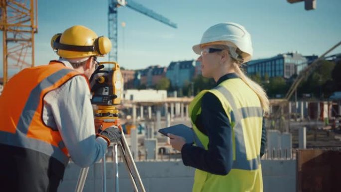 建筑工人使用经纬仪测量光学仪器测量建筑工地上水平和垂直平面的角度。工程师和建筑师在测量师旁边使用平板