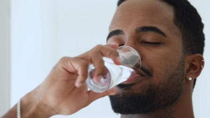 快乐的30岁非洲人饮用新鲜的纯净水。